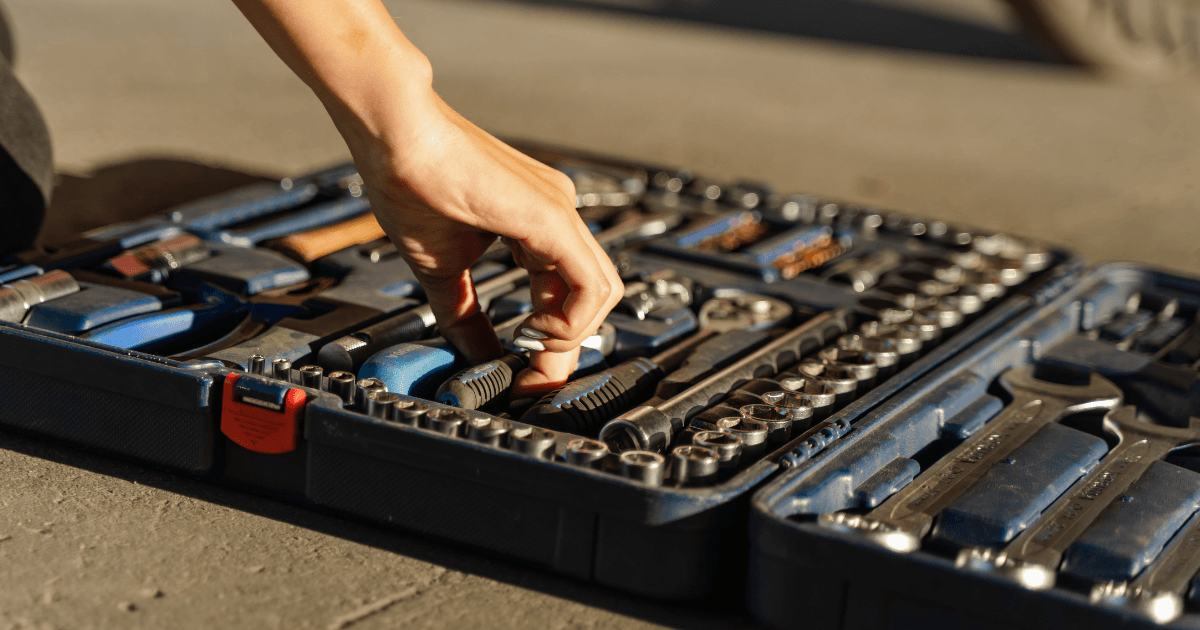 Open RV storage compartment showing an organized tool kit with wrenches, screwdrivers, and a multimeter
