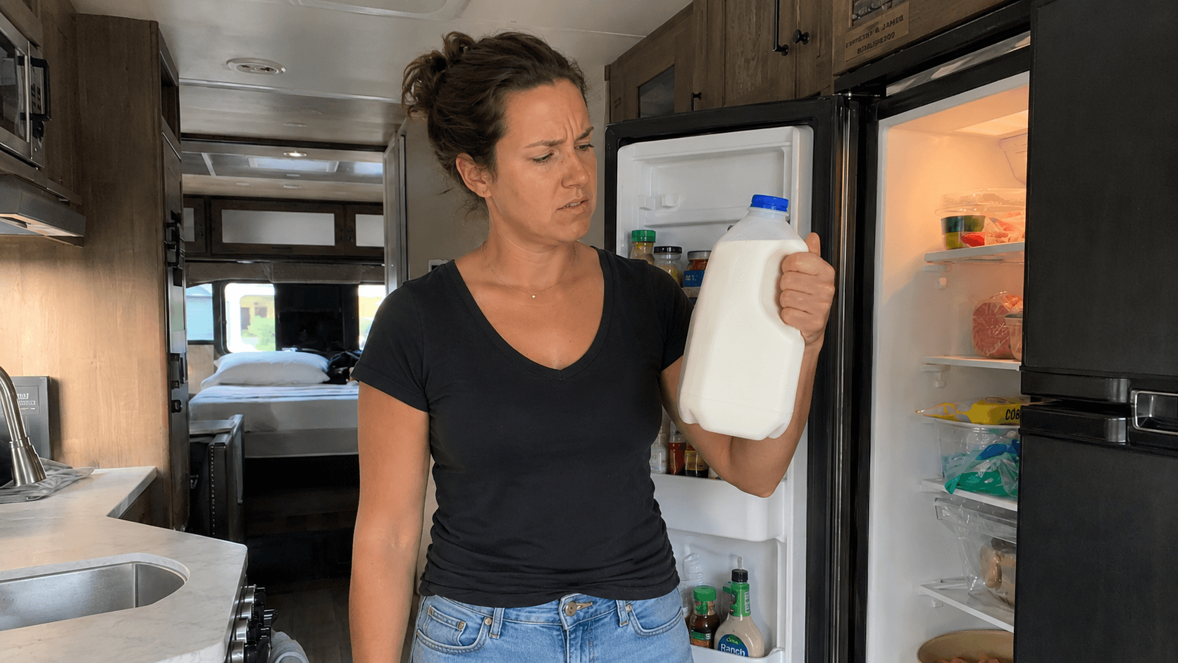 Woman holding a jug of milk in front of an open RV refrigerator