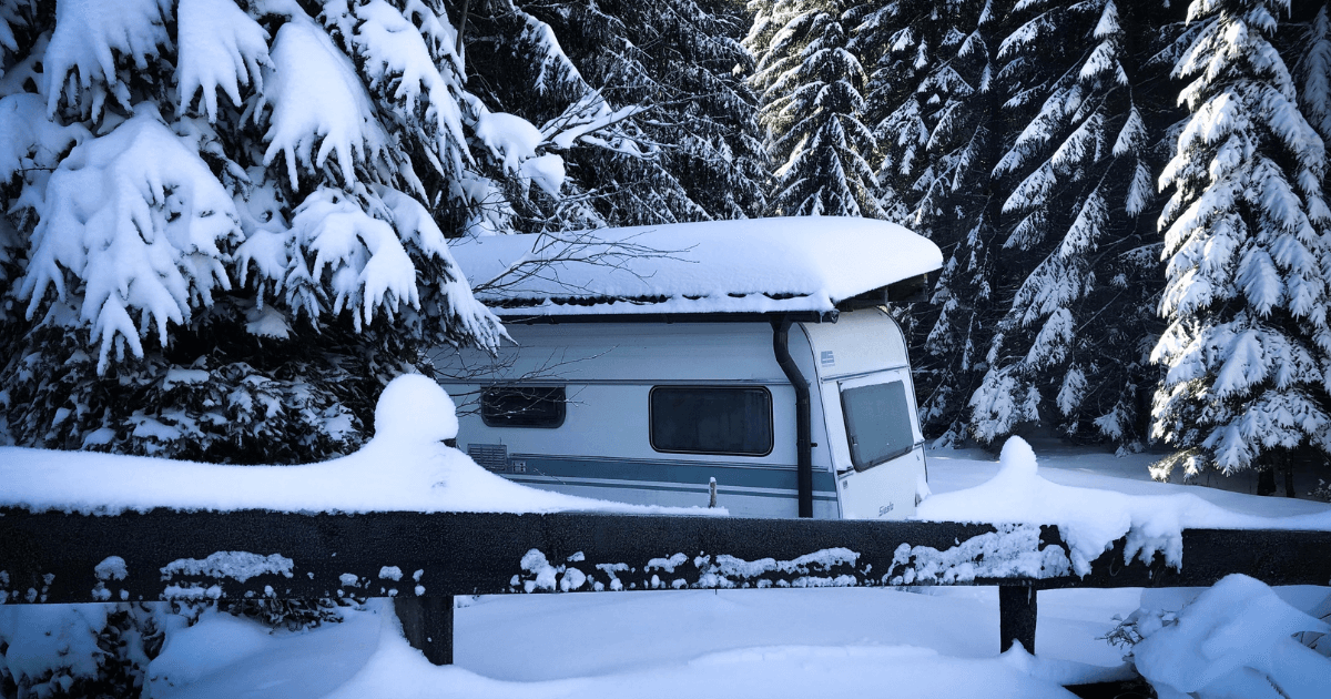 An RV parked in a snowy storage area with frost on the roof, ready for winter storage